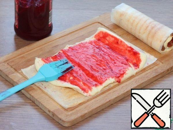 Unwrap the cooled roll and remove the paper. Place the unwrapped biscuit on this paper and spread with jam. Let soak for 1-2 minutes.