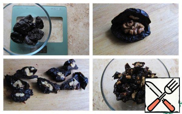 Wash and dry the prunes. Peel the walnuts and dry them in the oven or in a frying pan. Cut the prunes lengthwise, put the nut inside, cut into small pieces. The nut cut in this way will not be soaked with cream, it will remain crispy.
