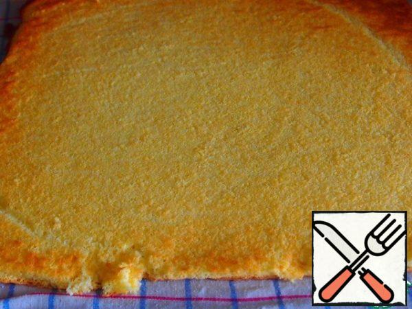 Transfer the finished biscuit to a slightly damp towel, covering the top with paper. Run wet hands over the paper a couple of times and carefully remove it. Wrap the sponge cake with a towel in the form of a roll and leave to cool.