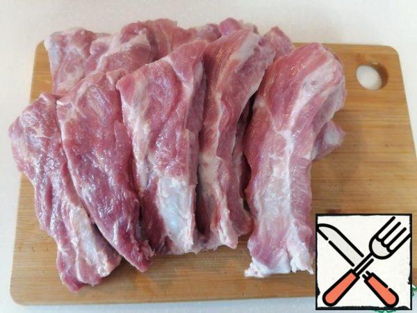 As soon as the beans are ready, we will start the meat. Cut the ribs into portions.