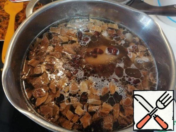 Our meat is cooked, we take out onions and carrots from the broth. I throw away the onion, and boiled carrots can be added to the salad.
Put potatoes and mushrooms, beans in the broth.