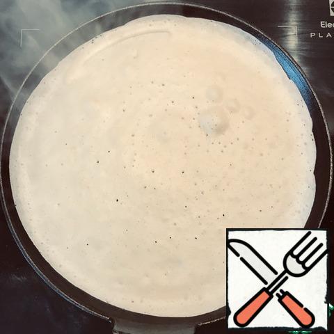Ladle out the dough and quickly distribute it over the pan, tilting it at different angles. We wait for the moment when the dough stops glistening and becomes velvety.