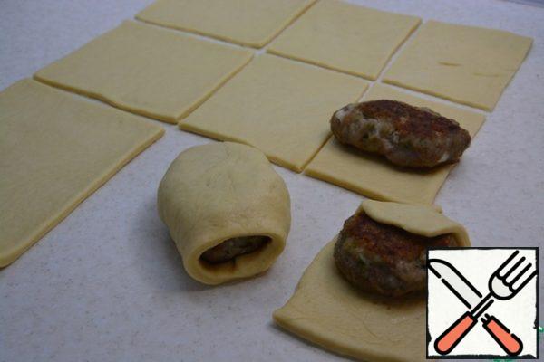 Roll out the dough. Cut it into rectangles so that you can wrap the cutlet in them. Pinch the edges. Lay the layer down on a baking sheet. Let it brew for 30 minutes.