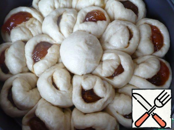 Put a ball in the middle of the pie (put a few pieces of raisins and 1 teaspoon of apricot jam on a circle of dough in the center, pinch the dough well and form a ball).