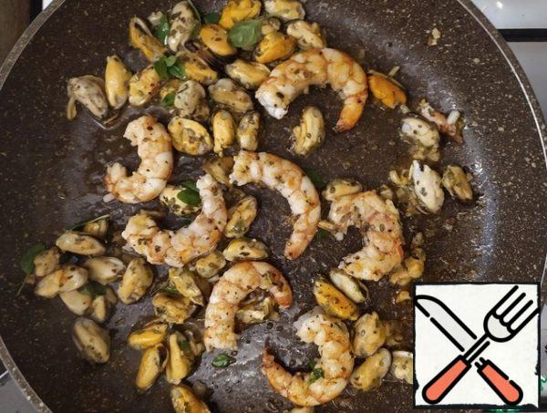 Fry the garlic in oil. We will add shrimp with mussels, as well as oregano and basil.