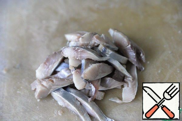 We clean the salted herring, cut it into fillets and cut it into thin strips.