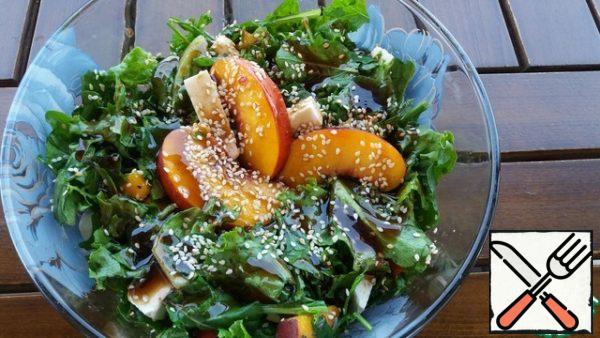 Put the greens, peaches and cheese in a salad bowl, add salt and pepper, and mix. Pour the sauce and sprinkle with sesame seeds.