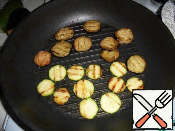 Fry the sliced zucchini and eggplant slices until browned on the grill pan on both sides in olive oil, season with salt and pepper to taste. Remove the vegetables from the heat. In the same pan, fry the chopped cherry halves.