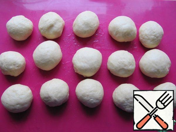 Put the finished dough on the work surface, which is greased with vegetable oil. Divide the dough into portions, in my case it is 15 pieces of 60 g (approximately). Roll each piece into a bun, leave it under the film for 5-10 minutes to make it easier to roll the dough into a layer.