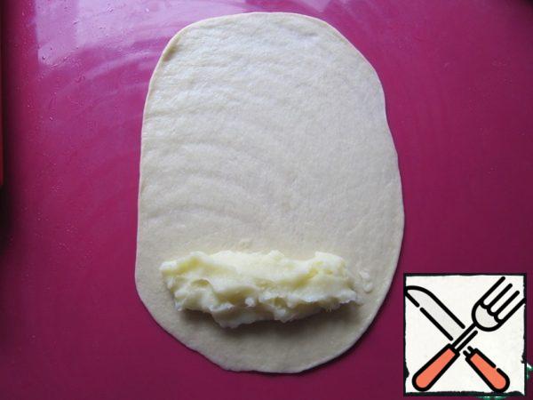 Roll out each piece into an oval with sides about 20 and 10 cm, lay out a portion of cream (1 tbsp), retreating slightly from the edges.