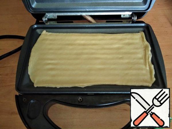 Insert the grill panels into the multi-Baker. Turn on the multi-cook, wait for the green indicator to light up and you can start cooking. Place the dough layer on the bottom panel.
