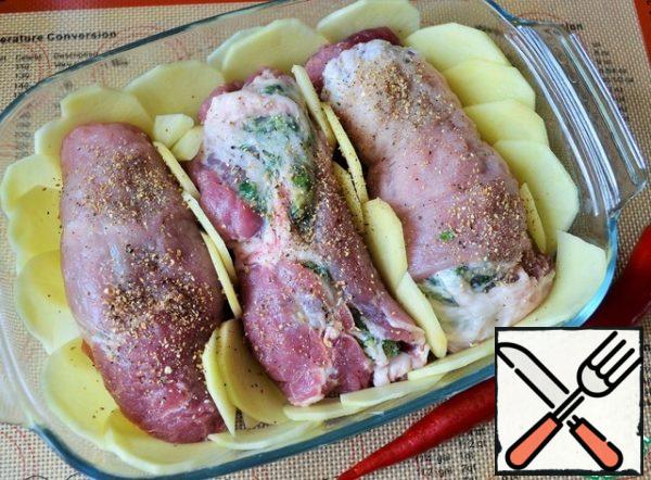 Grease the form with 1 tbsp of butter.
Peel the potatoes and garlic, cut into thin slices, lay out the bottom and walls of the mold. Put the rolls on the potatoes and pepper them.