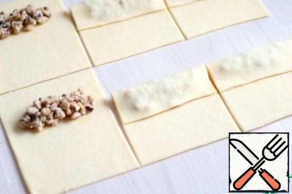 The prepared filling of chicken and mushrooms put on rectangles of dough, turn the edge to the center, slightly press.