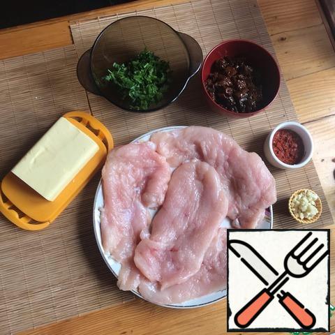 Prepare the products. Each fillet was cut in half lengthwise and beaten off. Sun-dried tomatoes sliced. Mixed paprika, salt and 3 crushed garlic cloves to grate the bird. Another 4 cloves crushed with a sauce knife. Chop the parsley, too.