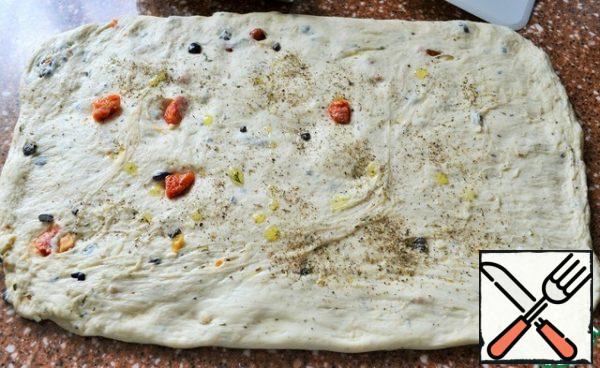 With your hands, flatten the dough into a rectangle, 20*45-50 cm., pour 1 tsp of olive oil, sprinkle with Italian herbs.