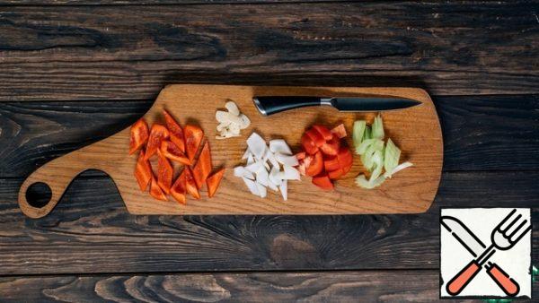 Prepare the vegetables for the stew: coarsely chop the onion and bell pepper, peel and cut the celery into slices, remove the skin from the tomatoes and chop them into cubes.