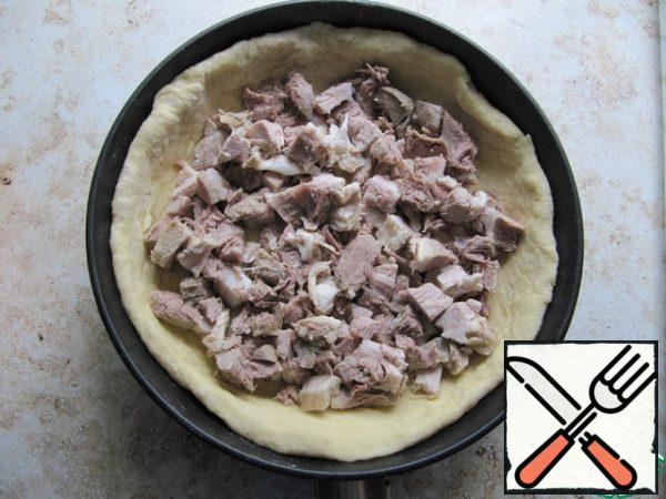 Grease the form with butter, dust with flour, shake off excess. Divide the dough into two parts, from a larger piece (2/3), roll out the base of the pie, laying out the bottom and sides of the form with the dough. Put the sliced meat on the bottom.