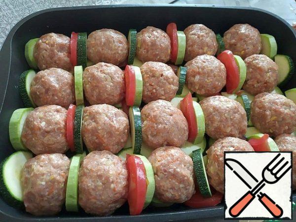 From the minced meat, we form meat balls and put them on the vegetables. Place the remaining vegetables between the meatballs.