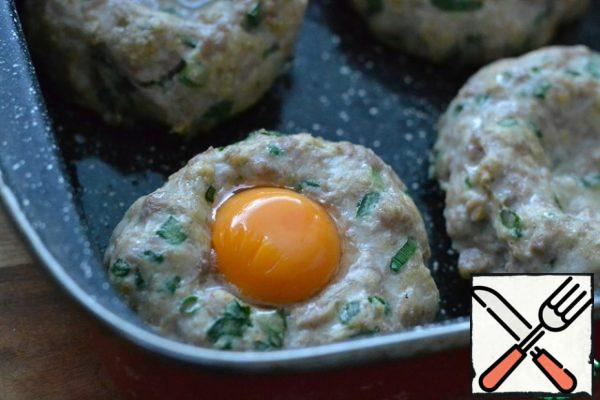 Take the pan with the cutlets out of the oven and carefully pour the egg yolk into each recess.
