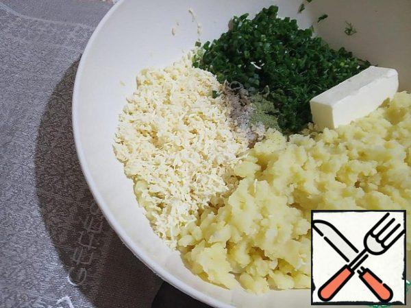 Puree the potatoes, grate the cheese on a small grater. Add 50 g of softened butter, finely chopped green onions and dill, salt and spices. Mix thoroughly.