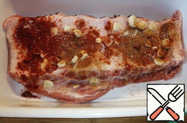Sprinkle the pork ribs with smoked paprika, ajika, and salt to taste. Add the garlic cut into circles and pour over the olive oil. RUB the ready-made spice mixture into the ribs on both sides and put it in the refrigerator for a few hours.