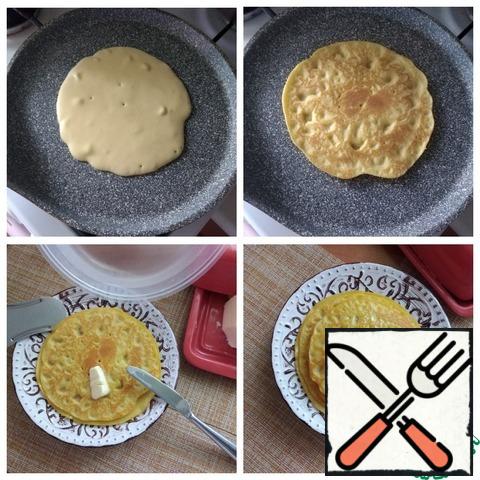 Start baking pancakes. Pancakes will be plump and D~ 12-13 cm. Heat the pan well and pour the dough from the center of the pan as much as you want to bake a pancake. It will spread itself out flat, you will see. It is very convenient to have dishes for dough with a spout, then you will not need to use a ladle. Pancakes are baked on medium heat. When the pancake is browned and grabs, turn it over and fry until ready on the other side. Spread in a plate and smear with a piece of butter. From corn flour pancakes are obtained dry, oil will soften them. Even after removing each pancake on a plate, cover it with a cap. This amount of dough made 6 pieces of thick pancakes D~12 cm.