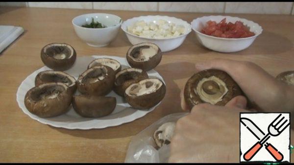 Take the mushrooms and release the cap from the leg. Mushrooms take the largest, they will decrease when baking.