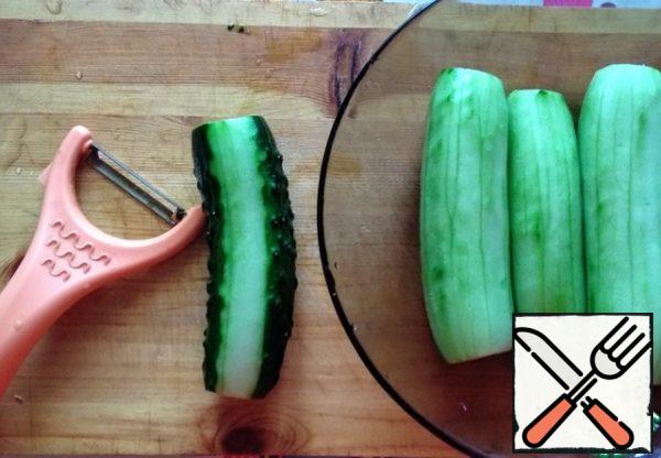 Wash the cucumbers and peel them with a vegetable peeler.