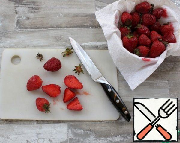 Wash the strawberries, dry them on a paper towel, and cut them in half.