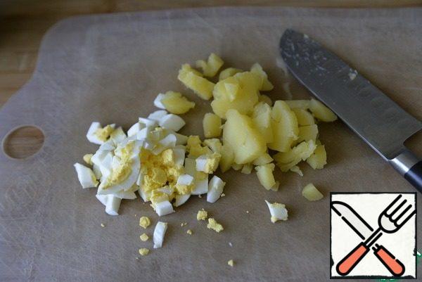Boiled eggs and potatoes are cleaned and cut into cubes.