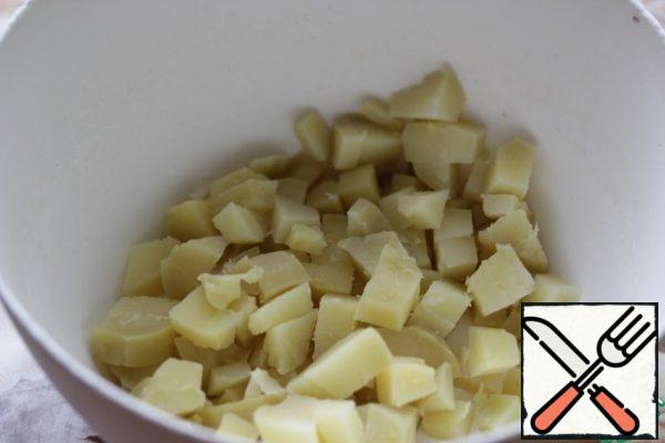 Boil the potatoes in the "uniform", cool a little and peel them.
Cut into pieces and sprinkle with vinegar.