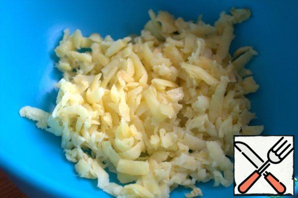 Boil the potatoes, peel them, and grate them coarsely.