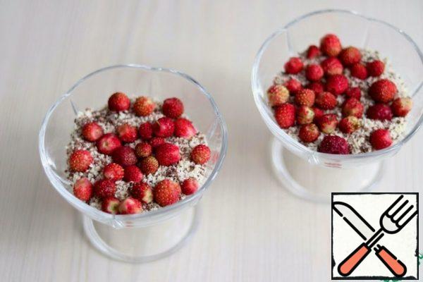 Add a small amount of cream to the bottom of the cremans, sprinkle with a layer of milk and white chocolate, grated on a grater. Next, lay out the wild strawberry berries and again lay out a layer of butter cream.
Put the dessert in the refrigerator to cool and stabilize the dessert.