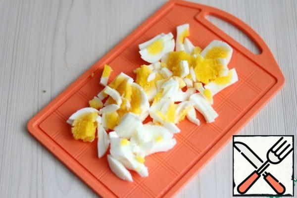 Boil the eggs and cut them into strips.