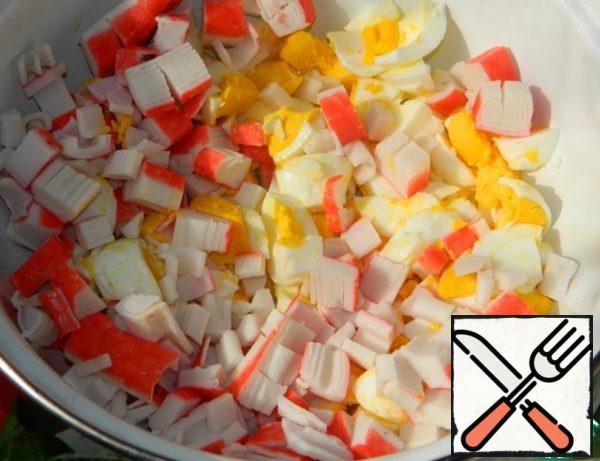 Cut the eggs and crab sticks not quite fine.