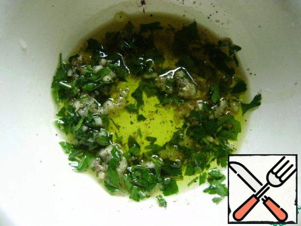 Make the dressing. To do this, finely chop the greens. You can take any greens, I have parsley. Garlic is squeezed out on a garlic press. Add olive oil. Sprinkle with salt and pepper to taste.