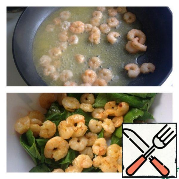 In a hot pan, pour a little oil and the juice of half an orange. Lay out the prawns and fry for 3-4 minutes.
In a salad bowl, put the washed and dried spinach leaves, and send the fried prawns to the same place.