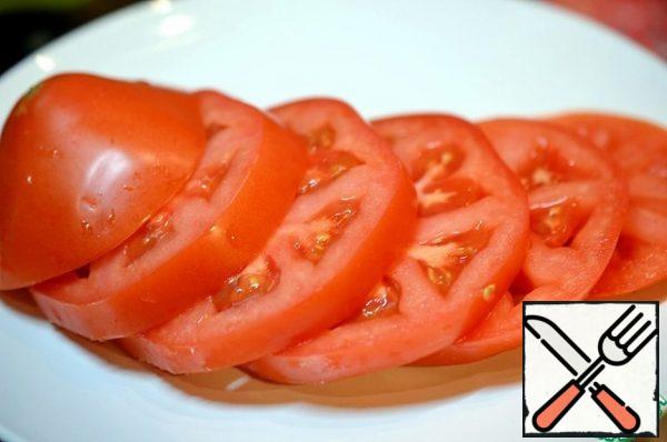 Cut the tomato into circles and put it on a plate.