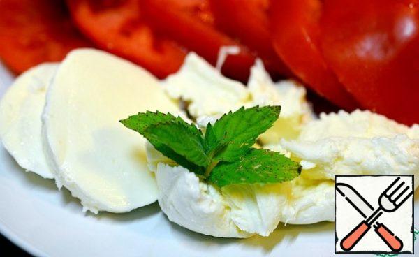 Cut the mozzarella into circles or just tear it with your hands and put it on top of the tomatoes. Garnish with mint and arugula leaves.