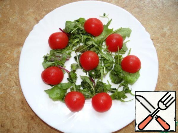 Chop the greens coarsely, put them on a plate, add the tomatoes, cut in half;