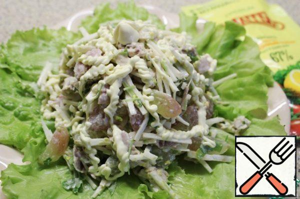 Put the salad on a hill on the lettuce leaves, decorate, sprinkling the salad with onions, thin strips of mayonnaise and grapes.