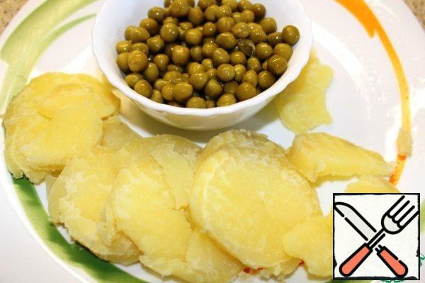 Potatoes-slices, canned peas throw in a colander, drain the liquid.