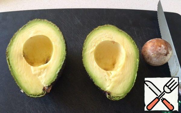 Take the ripe avocados and cut them in half. Remove the bone.