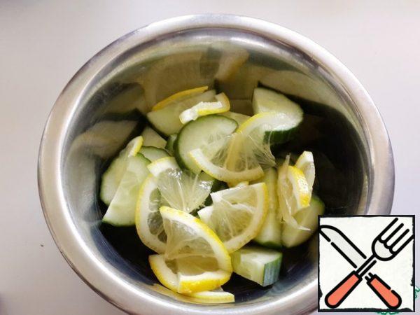 Cut the cucumbers into half-rings, and the lemon into thin, thin slices.