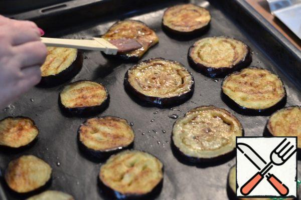 Each circle of eggplant is greased with prepared sauce.