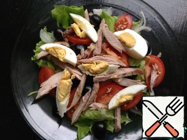 Cut the half of the tomato into thin slices.  Cut the egg into 6 slices.  Cut the chicken drumstick into thin strips.  We carefully lay out everything on the salad.