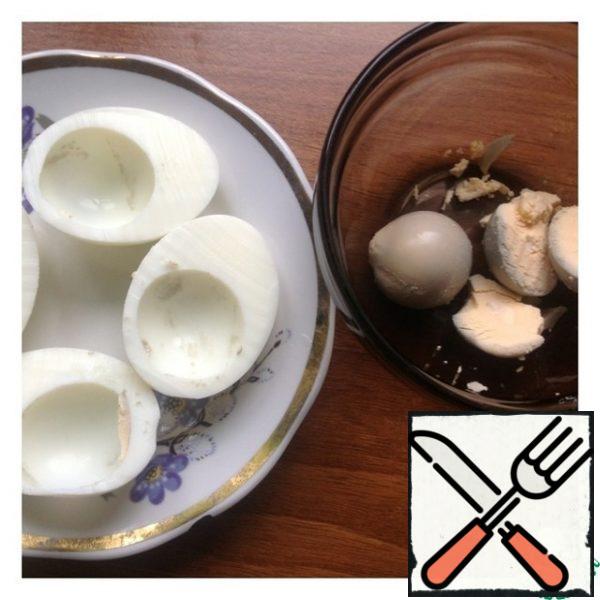Peel the eggs and cut them lengthwise. Carefully pull out the yolk and transfer it to the bowl.