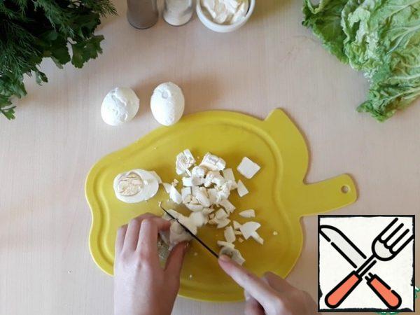Finely chop the hard-boiled chicken eggs and add them to the cucumbers with corn and crab sticks.