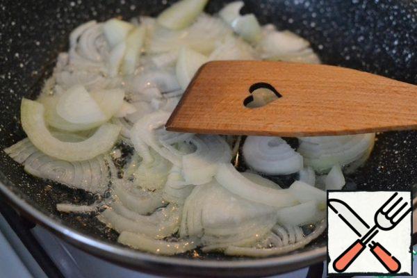 In a frying pan on sunflower oil, fry the onion, cut into half rings.
