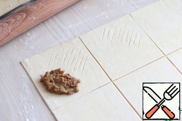 Roll out the puff pastry into a layer. Cut the dough layer into squares of equal size. The approximate number of squares is 16-18 pieces.